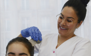 Professionnelle utilisant un peigne à poux pour vérifier les cheveux d'une patiente.